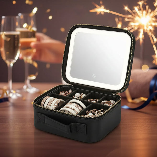 Black jewelry case with a mirror lid containing jewelry items on a white background