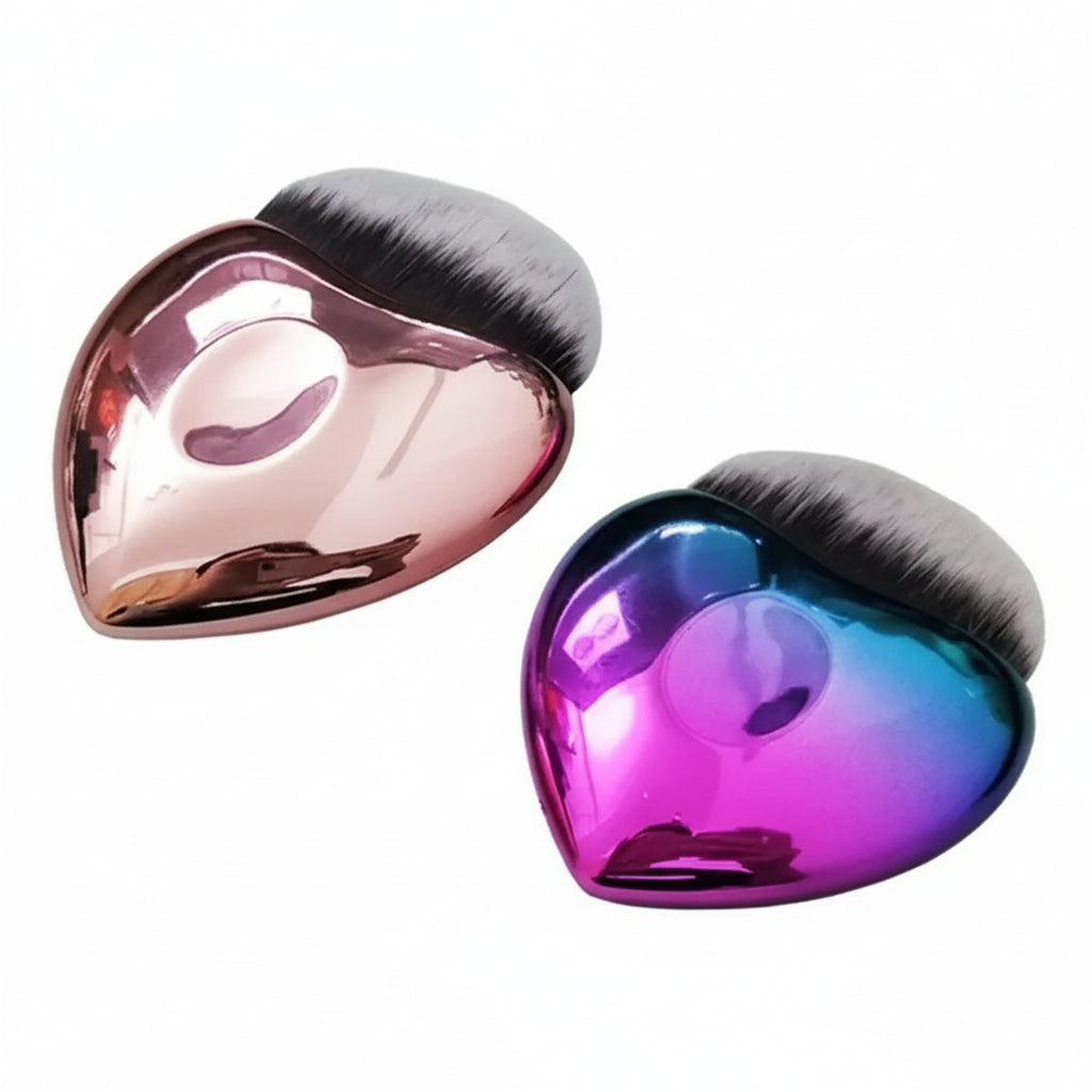 Two heart-shaped makeup brushes with metallic pink and blue finishes on a white background